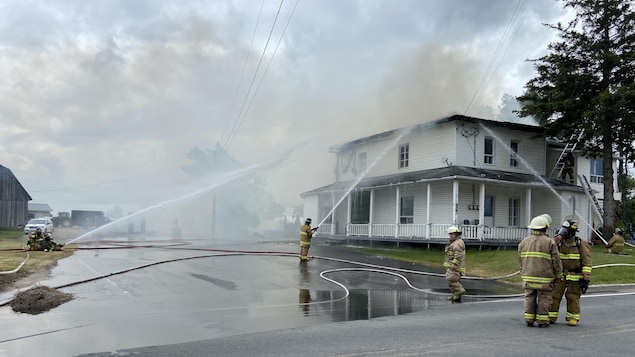 Des pompiers arrosent une maison.
