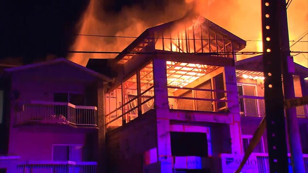 Un édifice, dont une partie semble en construction, est la proie des flammes. Un édifice, dont une partie semble en construction, est la proie des flammes.