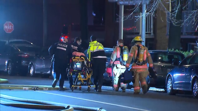 Des pompiers et des policiers transportent une civière.