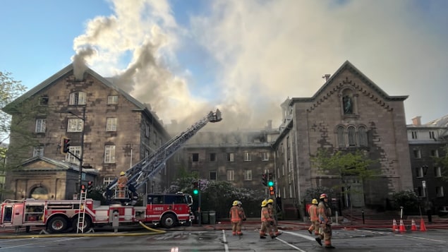 La fumée s'échappe du toit d'un bâtiment en proie aux flammes.