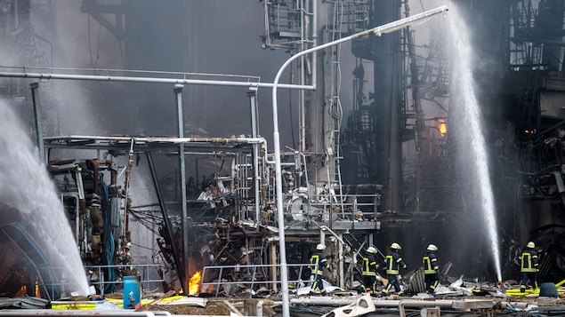 Un groupe de pompier sur une immense scène d'incendie industriel. Ils semblent petits face aux installations pétrochimiques. Un groupe de pompier sur une immense scène d'incendie industriel. Ils semblent petits face aux installations pétrochimiques.