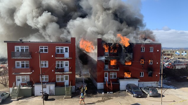 Une épaisse fumée noire sort d'un immeuble de logements en flammes.