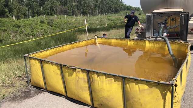 Un pompier surveille le remplissage d'un réservoir.