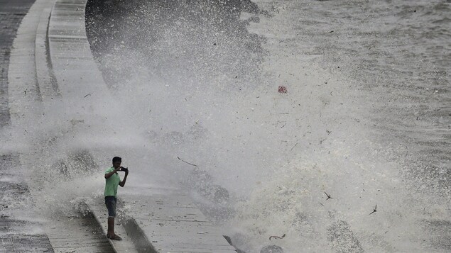 Un homme prend une photo très près de grosses vagues. Un homme prend une photo très près de grosses vagues.