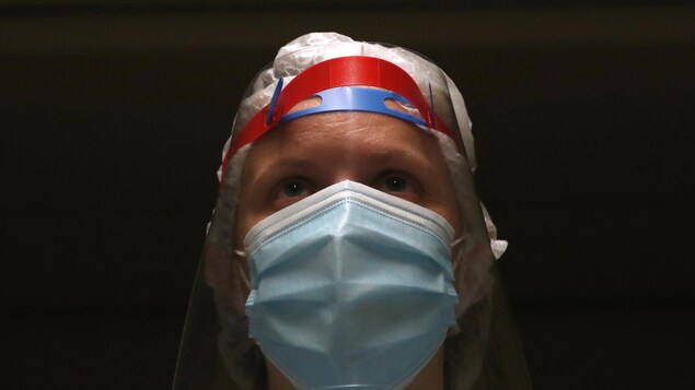 Portrait de face d'une infirmière portant un masque.
