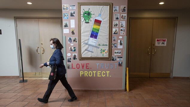Une infirmière passe devant un panneau qui fait la promotion de la vaccination au foyer des soins Villa Columbo de Toronto.