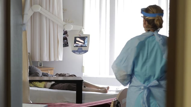 Une infirmière portant un équipement médical de protection entre dans la chambre d'une patiente dans un établissement de soins pour personnes âgées à Seattle le 17 avril 2020.