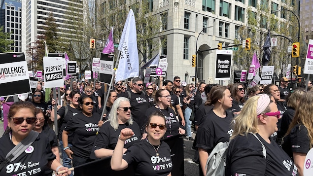 Des infirmières marchent en solidarité, portant des t-shirts qui réclament que 97 % ou plus de leurs membres votent en faveur d'une grève.