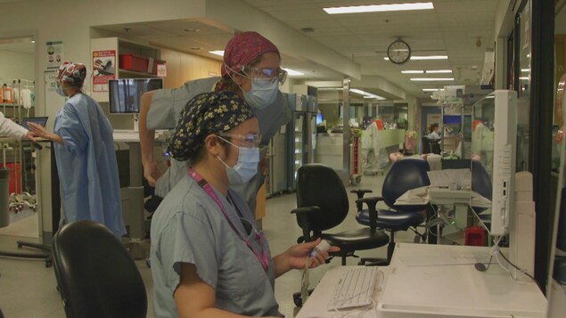 Deux infirmières de l'unité de soins intensifs à l'Hôpital Saint-Paul de Vancouver regardent l'écran d'un ordinateur.