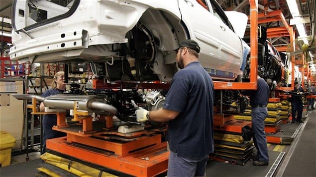 Des travailleurs de GM installent un pot d'achoppement à l'usine. Des travailleurs de GM installent un pot d'achoppement à l'usine.