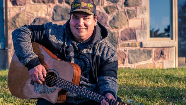 Keven Chouinard joue de la guitare à l'extérieur.