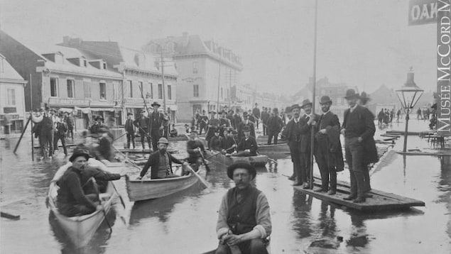 Des hommes dans une embarcation en 1886 lors de l'inondation à Montréal. Des hommes dans une embarcation en 1886 lors de l'inondation à Montréal.