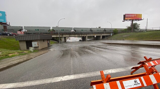 Des barrières interdisent l'accès à un tunnel inondé. On peut apercevoir une voiture bloquée par les eaux.