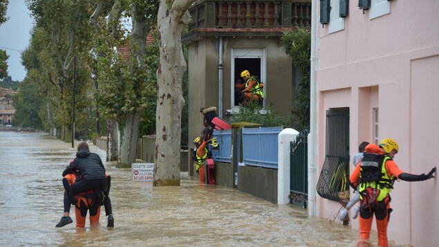 Des pompiers évacuent des sinistrés. Des pompiers évacuent des sinistrés.
