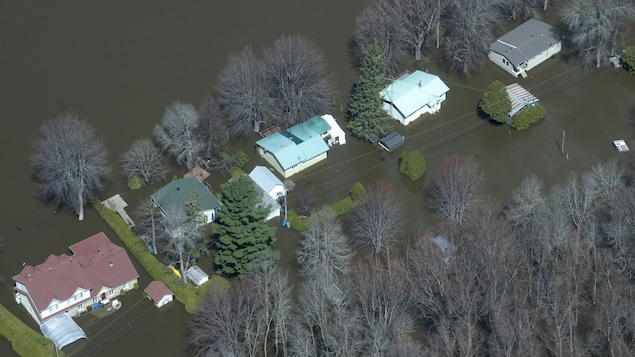 Vue aérienne de cinq maisons complètement entourées d'eau.