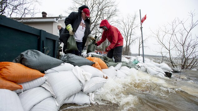 Des personnes installent des sacs de sable.