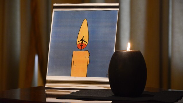 Une bougie brûle devant un dessin et un livre de condoléances à l'ambassade d'Ukraine à Ottawa.