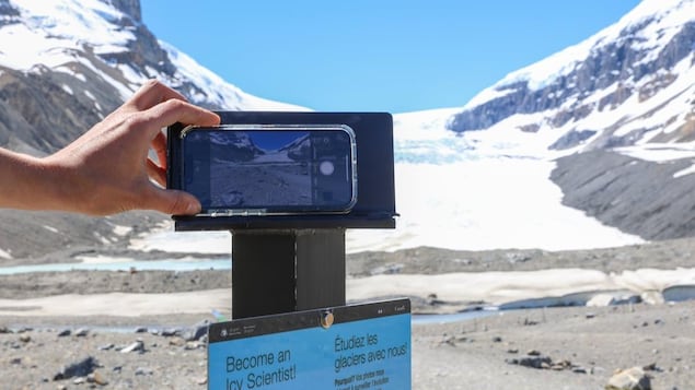A cellphone stand with a smartphone on it pointing to a glacier ahead.