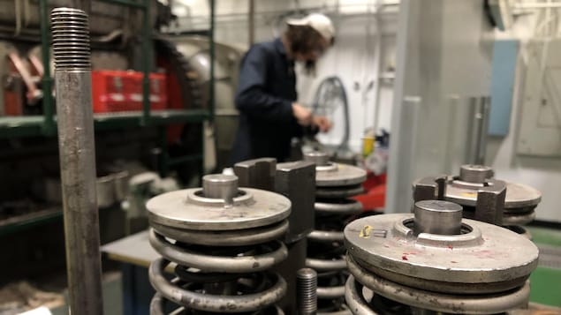 Un étudiant au travail derrière de gros ressorts en métal.
