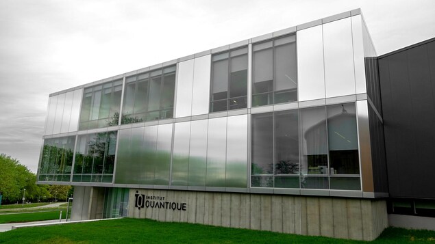 La façade d'un bâtiment a une forme rectangulaire et plusieurs fenêtres. Il s'agit de l'Institut quantique de l'Université de Sherbrooke, 