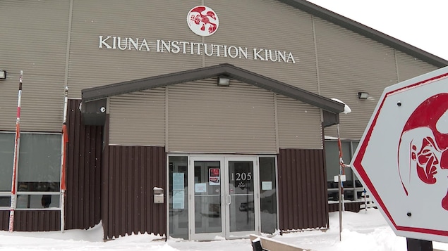 L'affiche de l'institution devant le bâtiment en hiver.