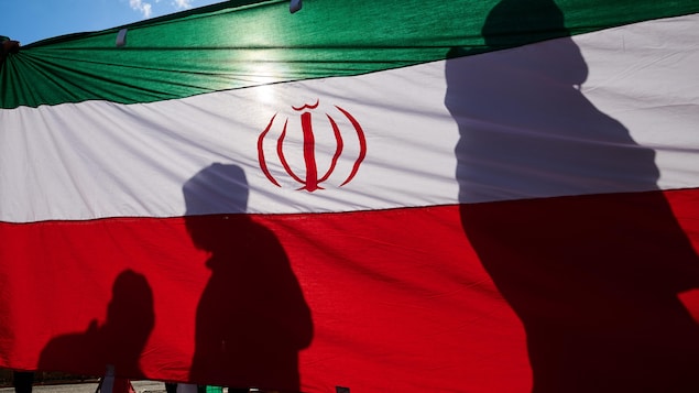 Des manifestants passent devant un drapeau national iranien.