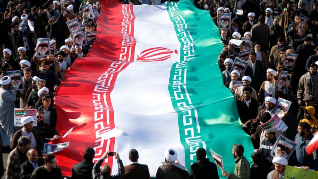 De nombreux Iraniens, dont des mollahs, entourent un drapeau de la République islamique à Qom. De nombreux Iraniens, dont des mollahs, entourent un drapeau de la République islamique à Qom.