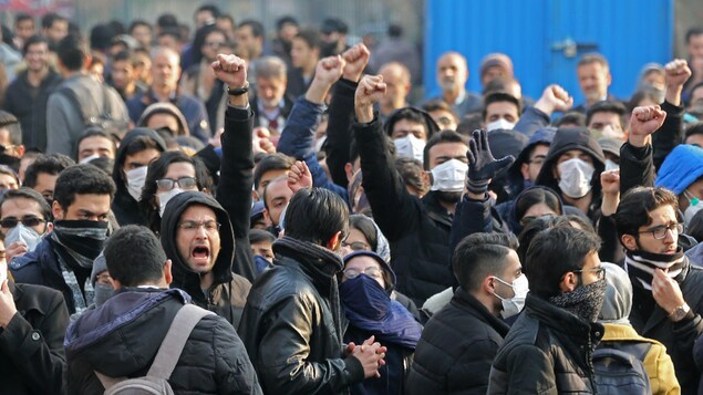 Des dizaines d'étudiants, masqués pour la plupart, crient des slogans ou brandissent un poing en l'air.