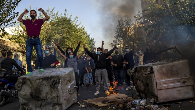 Des hommes lèvent les bras en l'air près d'une barricade établie dans une rue.