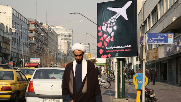 Un religieux marche près d'une affiche montrant des coeurs relâchés par un avion.