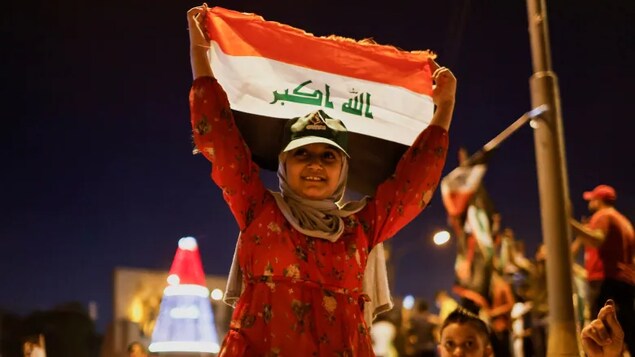 A person holds an Iraqi flag, as supporters of populist Shia cleric Muqtada al-Sadr's movement celebrate after preliminary results of Iraq's parliamentary elections were announced in Baghdad on Monday.