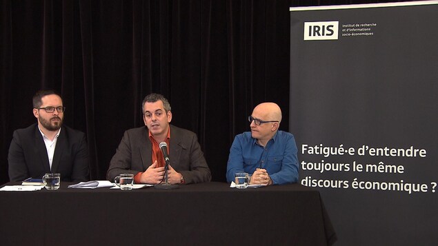 Des chercheurs en économie, dont le professeur Marc-André Gagnon (au centre, au micro), et le médecin Alain Vadeboncoeur, en conférence de presse à Montréal. Des chercheurs en économie, dont le professeur Marc-André Gagnon (au centre, au micro), et le médecin Alain Vadeboncoeur, en conférence de presse à Montréal.