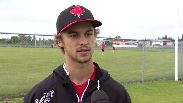 Isaac Lefebvre parle en entrevue à la caméra devant un terrain de baseball. Isaac Lefebvre parle en entrevue à la caméra devant un terrain de baseball.
