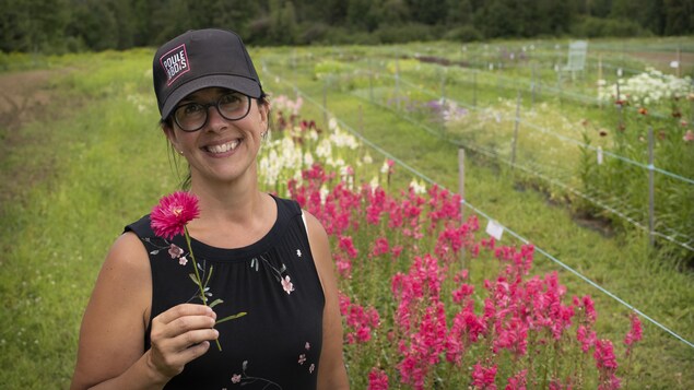 Isabelle Forgues avec une fleur dans les mains, dans un champ de fleurs.