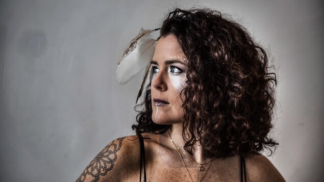 La femme arbore un maquillage original et une plume d'aigle aux cheveux. La femme arbore un maquillage original et une plume d'aigle aux cheveux.