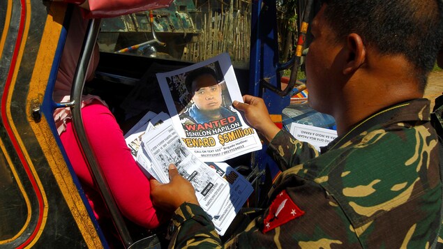 Un soldat regarde la photo d'Isnilon Hapilon. Un soldat regarde la photo d'Isnilon Hapilon.
