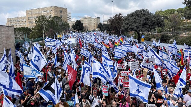 Des milliers de personnes brandissant le drapeau d'Israël dans une vaste manifestation.