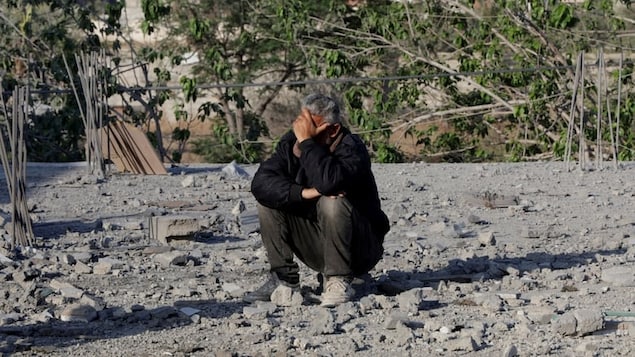 A Palestinian man sits on debris while covering his face with his hand at the site of an Israeli strike in Khan Younis in the southern Gaza Strip on Monday. 