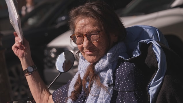 Une femme vend un journal sur le coin d'une rue.