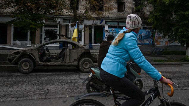 Une femme roule à vélo dans une rue.