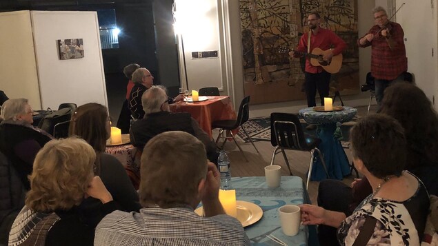 Deux musiciens font un spectacle de musique devant plusieurs personnes.