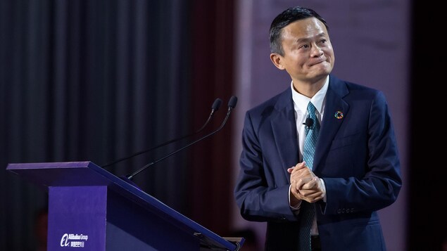 Jack Ma livre un discours sur une scène en souriant et regardant vers la droite.
