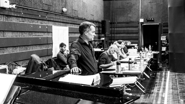 Jacques Lacombe accoté sur un piano, aux côtés de toute l'équipe de l'opéra Jacques Lacombe accoté sur un piano, aux côtés de toute l'équipe de l'opéra