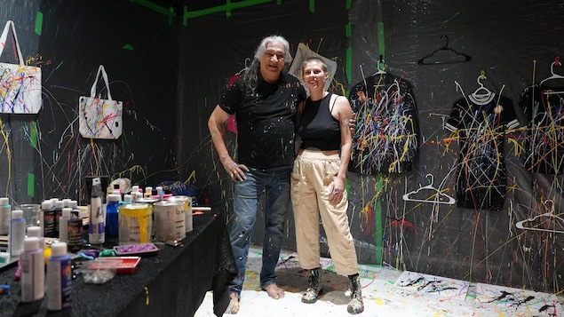 Les deux personnes debout devant des objets peinturés et des pots de peinture.