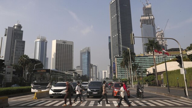 Des gens traversent une rue dans un quartier économique de la capitale indonésienne, Jarkarta.

