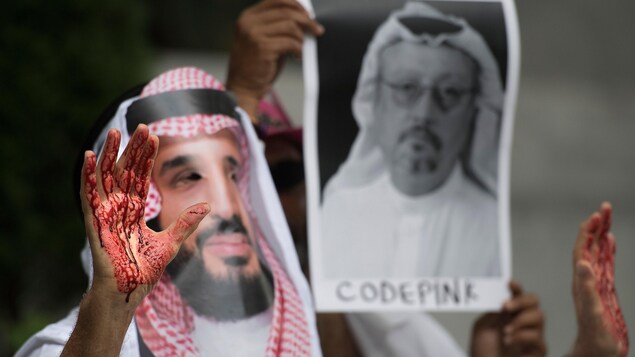 Un homme portant un masque de Mohammed ben Salmane lève ses mains ensanglantées.