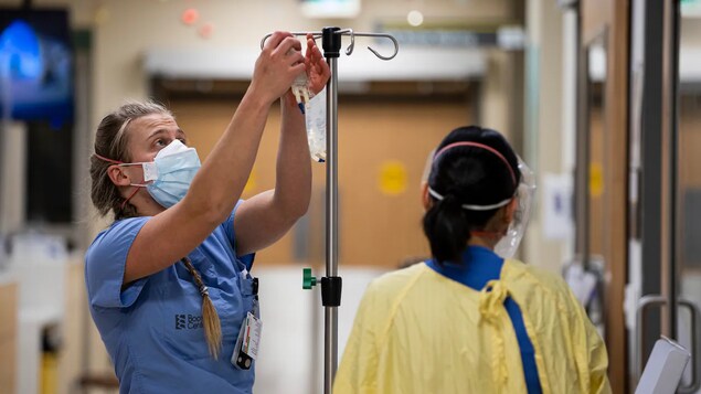 A nurse hangs a bag of IV medicine.