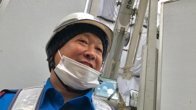 Ce journalier porte un casque de construction et un masque.