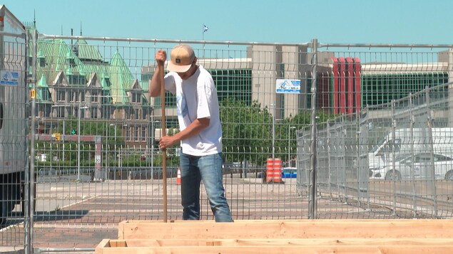 Un homme place de la terre dans les bacs des Jardins du bassin Louise.