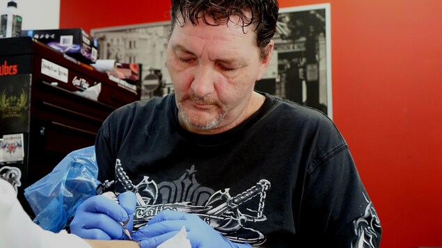 Un homme âgé dans la fin de la quarantaine est en train de faire un petit tatouage sur un poignet. Un homme âgé dans la fin de la quarantaine est en train de faire un petit tatouage sur un poignet.